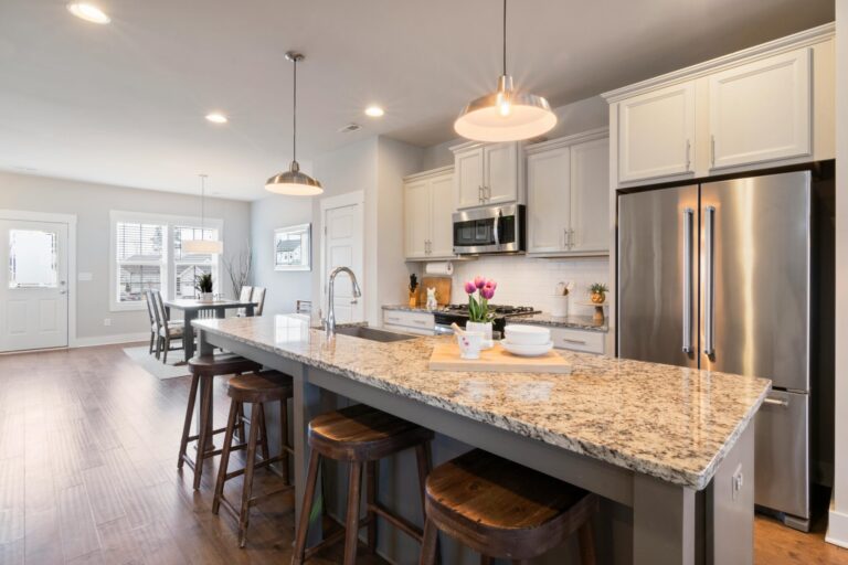 clean kitchen area with amber lights and stainless steel appliances