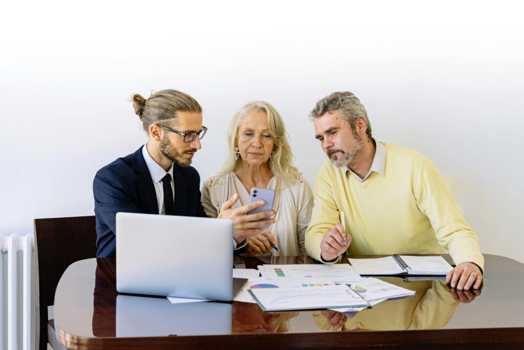 a man and woman sittting on a table with a lot of paper and laptop on the side