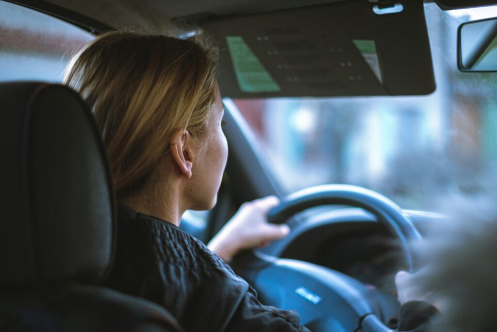 a woman sitting in a car holding the steering wheel